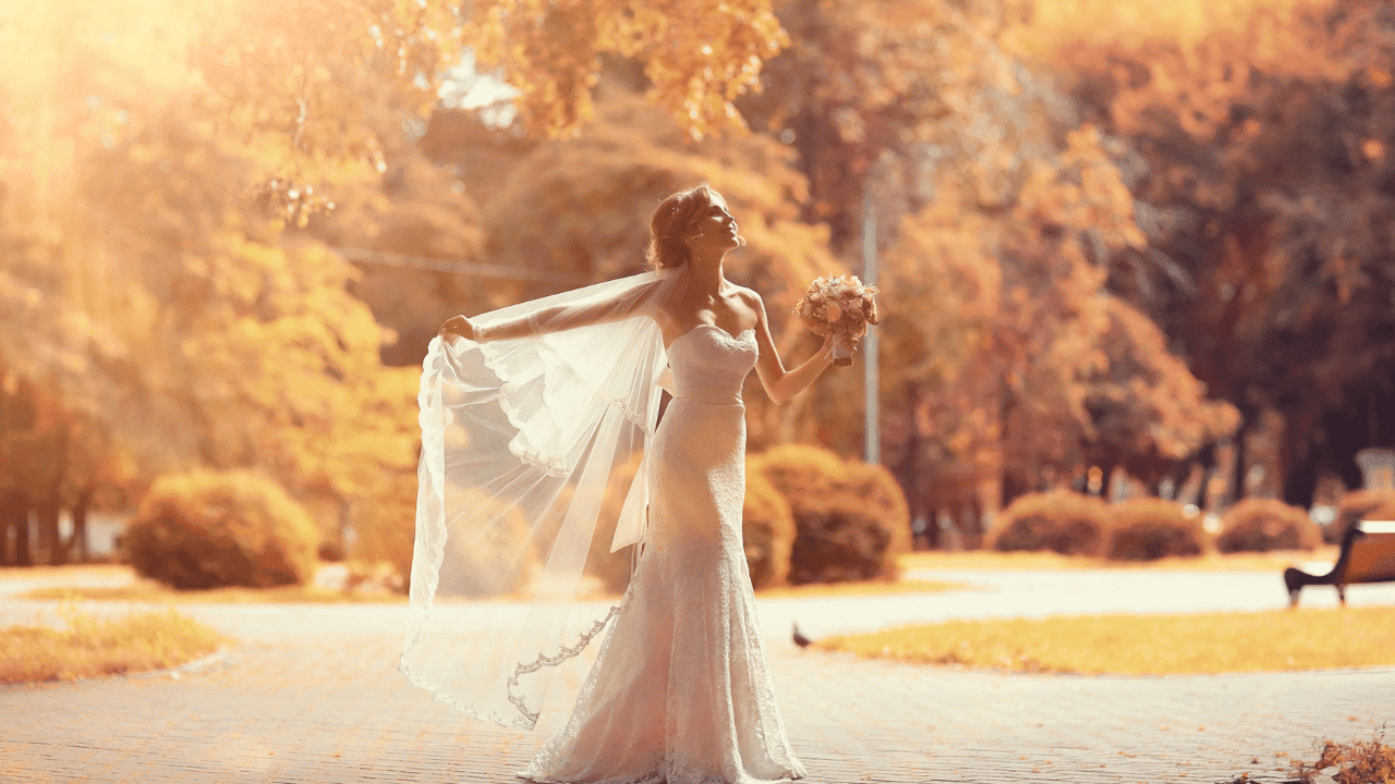 A bride wearing a wedding dresses standing outside.