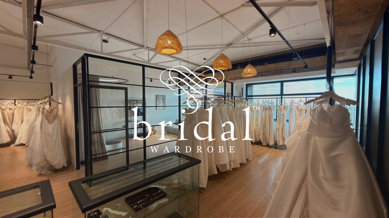 Bridal Wardrobe boutique interior with luxury wedding dresses displayed on rails and a featured bridal gown in the foreground.