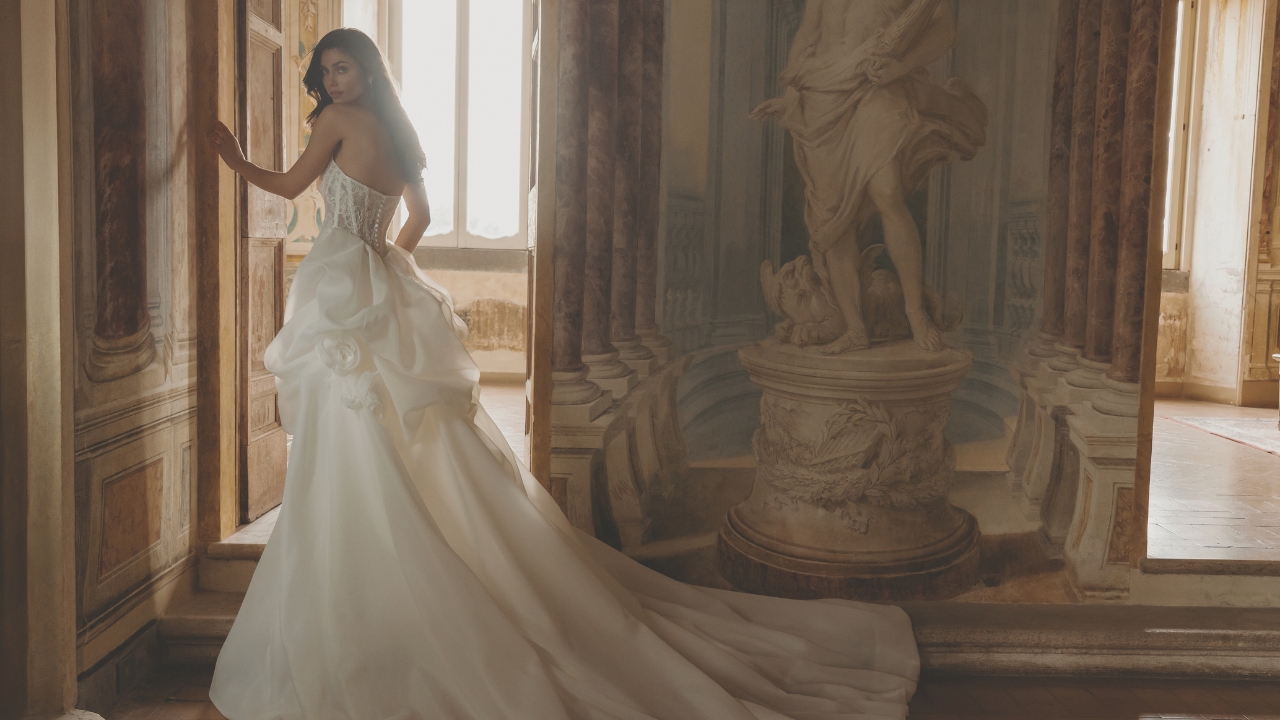 Bride wearing a luxurious wedding gown in an elegant historic venue with flowing train