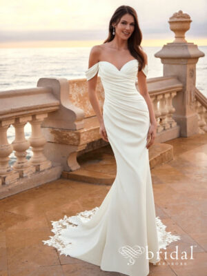 Bride wearing the FIE column wedding dress from the Love collection in luxury crepe with a sweetheart neckline, off-the-shoulder sleeves, ruched bodice and lace chapel train.