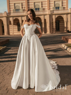 Bride wearing the UDELL Blue by Enzoani ballgown wedding dress with a sweetheart neckline, floral off-the-shoulder sleeves, crumbcatcher bodice, basque waist and cathedral train.
