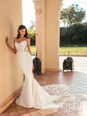 Bride wearing the UMORA Blue by Enzoani column wedding dress with beaded 3D flowers, scoop sweetheart neckline, spaghetti straps, basque waist and chapel train.