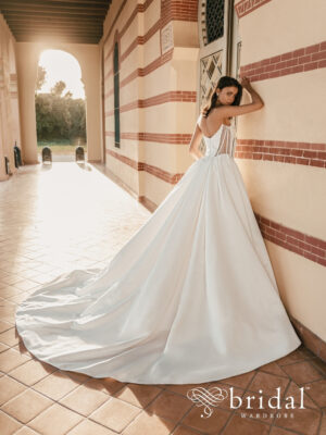 Bride wearing the USHA Blue by Enzoani ballgown wedding dress with an embellished sweetheart crumbcatcher bodice, sheer side cutouts, basque waist and royal train.