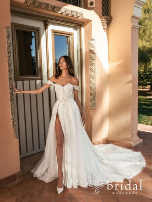 Bride wearing the UVENA Blue by Enzoani A-line wedding dress with a sweetheart neckline, off-the-shoulder sleeves, princess-boned bodice, basque waist, hidden high slit and royal train.