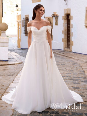 Bride wearing the FRALINA A-line wedding dress from the Love collection with off-the-shoulder sleeves, a sweetheart crumbcatcher bodice, basque waist and cathedral train.