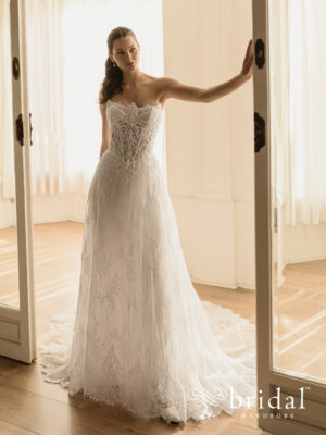 Bride wearing the HILINA Élysée A-line wedding dress with a strapless scalloped scoop neckline, princess-boned bodice, basque waist and cathedral train.