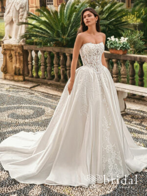 Bride wearing the WINDSOR by Enzoani ballgown wedding dress with a strapless semi-sweetheart neckline, basque waist, detachable beaded trim and sweeping cathedral train.