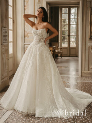 Bride wearing the WEST by Enzoani strapless ballgown wedding dress with a sculpted scoop neckline, princess-boned bodice, defined basque waist and cathedral train