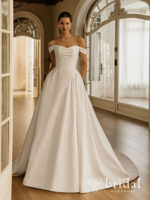 Bride wearing the HALIMA Élysée A-line wedding dress with a sweetheart neckline, off-the-shoulder sleeves, ruched bodice, pockets and a cathedral train.