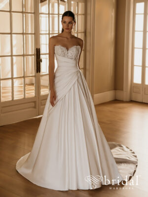 Bride wearing the HERMIONE Élysée A-line wedding dress with a sculpted sweetheart neckline, strapless ruched bodice, asymmetrical waistline and cathedral train.